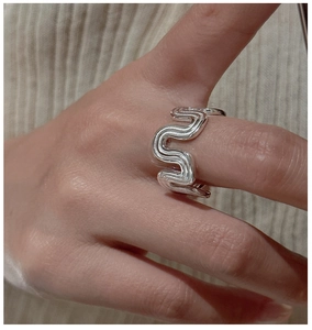 Macro shot of S925 silver ring featuring liquid metal wavy texture on index finger