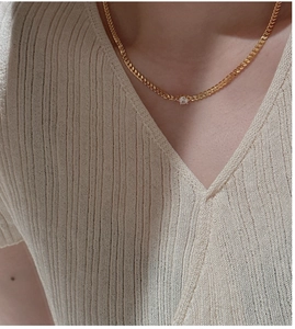 Close-up of a minimalist gold S925 silver necklace with a single zircon on a woman neck