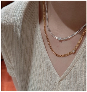 Detail of S925 silver and gold tank chain necklaces with a single round zircon on model