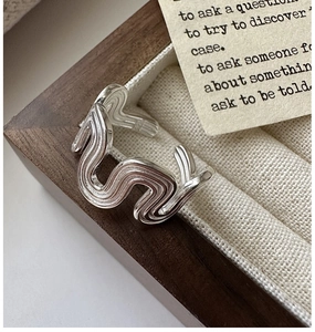 Macro shot of silver wave textured open ring placed inside a vintage wooden jewelry box