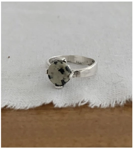 Macro detail of sterling silver ring featuring a round Dalmatian jasper stone in four-prong setting