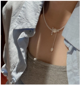 Detail of S925 silver beaded necklace with pearl pendant and OT buckle on linen shirt