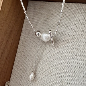 S925 sterling silver tassel necklace with matte beads and drop pearl on linen background