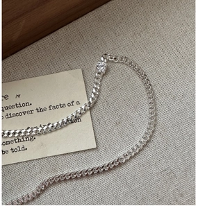 Macro shot of silver curb chain necklace with sparkling zircon on vintage linen background