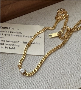 Close-up of gold tank chain necklace with a round zircon pendant and lobster clasp