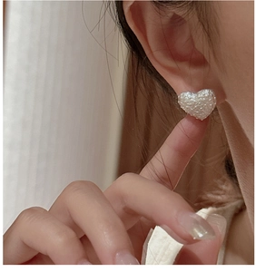 Close-up of S925 sterling silver heart-shaped stud earring with a textured white pearl finish