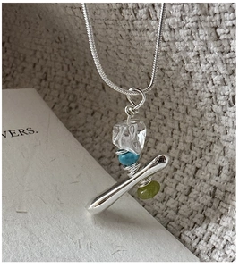 Detail of handcrafted silver snake chain with raw stone and colorful bead charms