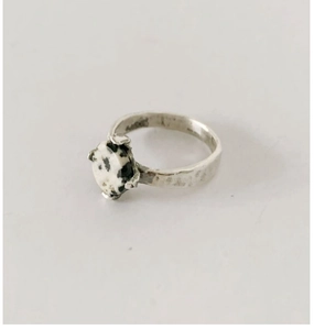 Detail of handmade silver ring featuring hammered texture and a round Dalmatian jasper stone