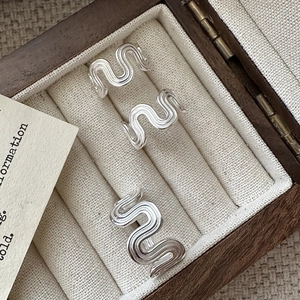 Three minimalist S925 silver wavy open rings with a brushed texture on a vintage box