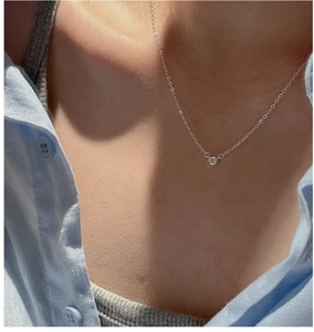 Close-up of minimalist S925 silver necklace with single bezel-set zircon on the collarbone