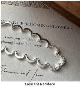 Close-up of S925 silver crescent moon necklace with matte finish on artistic card