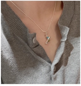 Detail view of S925 silver stacked necklace with irregular gemstone on a knitted cardigan
