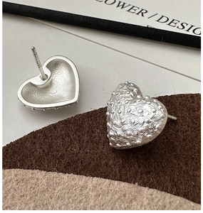 Close-up of S925 sterling silver heart studs with unique granulated texture and hallmark