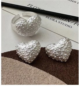Macro shot showing S925 sterling silver heart earrings and ring with studded texture