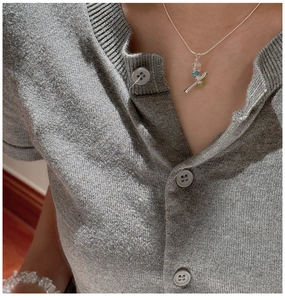 Close-up of minimalist S925 silver necklace featuring colorful raw stones on a grey cardigan