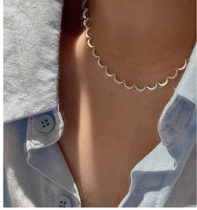 Detail of S925 sterling silver moon necklace with pavé stones on a blue linen shirt