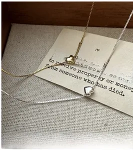 Vue détaillée de pendentifs cœur argent et or sur chaînes box sur papier vintage