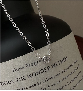 Close-up of S925 sterling silver chain with single zircon pendant on black bottle