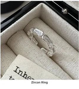 Close-up of a wavy S925 silver chain ring with zircon inlay on a beige fabric lining