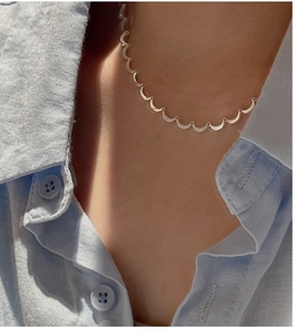 Detail of S925 sterling silver crescent necklace with zircons on blue linen shirt