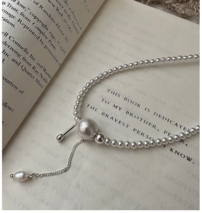 Detailaufnahme der Retro-Perlenkette mit mattierter Kugel und Perle auf offenem Buch