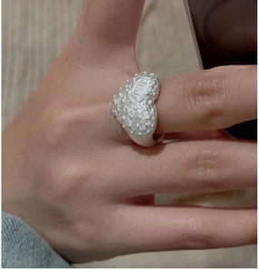 Detailed view of textured S925 silver heart ring worn on finger featuring grainy texture