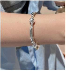 Detailed view of silver beaded elastic bracelet on wrist with striped melon beads
