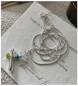 Detail of silver snake chain necklace with cross pendant featuring green beads and crystals