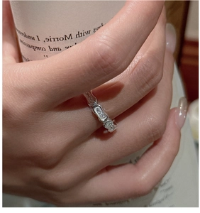 Macro shot of silver-tone zircon ring featuring wavy chain design on woman's finger