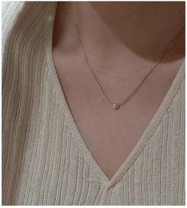 Gros plan d'un collier avec pendentif cœur en or rose minimaliste sur la clavicule