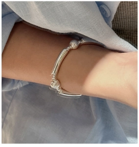 Detail of silver stretch bracelet with minimalist ribbed beads and curved tubes on wrist