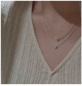 Vue détaillée de colliers superposés en argent 925 avec pendentifs cœur dorés et argentés