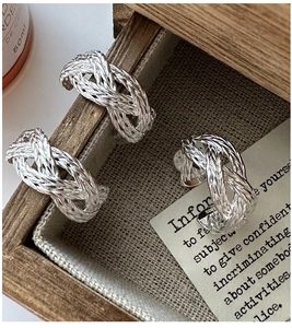 Detailed view of S925 sterling silver braided texture rings in a wooden tray