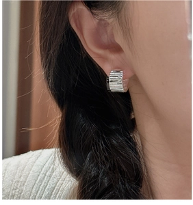 Detail of S925 sterling silver hoop earrings with a textured crinkle design and silver finish