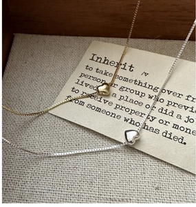 Détail de colliers avec pendentif coeur en argent et or dans une boîte en bois rustique