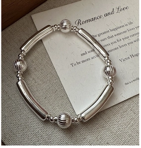 Detail of S925 silver beaded bracelet with sleek metallic tubes and striped round beads