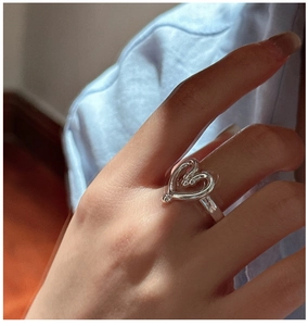Macro detail of minimalist S925 sterling silver hollow heart ring on finger
