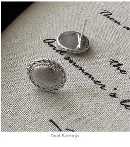 Macro shot of silver oval brushed metal earrings with twisted rope border detail