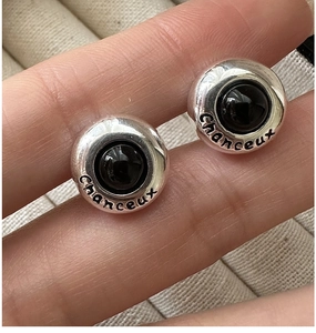 Close-up of S925 sterling silver earrings with black stone and Chanceux lucky engraving