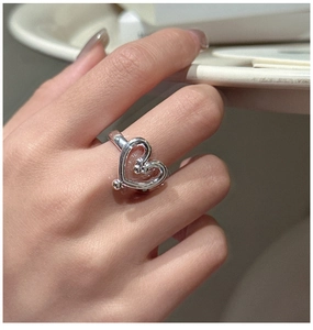 Detail of silver S925 heart ring with hollow design shown on model finger