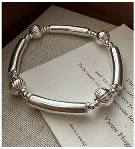 Macro detail of S925 sterling silver beaded bracelet with textured melon beads on vintage paper