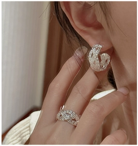 Detail of S925 sterling silver woven C-shaped earrings and matching ring on model
