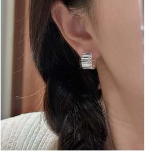 Macro detail of silver S925 earrings featuring a vintage pleated texture and wide-band design