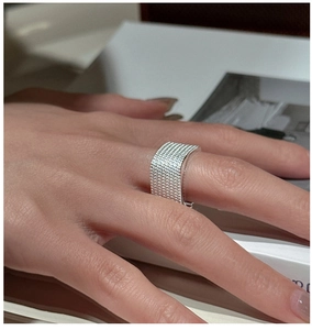 Detailed view of wide silver ring featuring a modern textured metal weave design