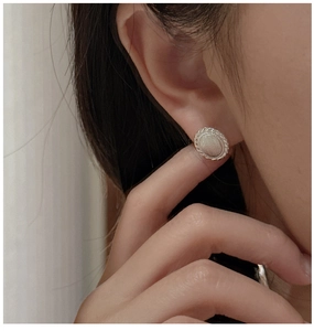 Close-up of S925 silver oval earrings with brushed texture and twisted rope edges