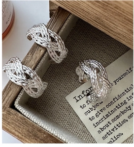 Detailed view of three-piece S925 sterling silver braided rings on a vintage wooden tray