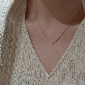 Collier cœur minimaliste en argent S925 porté par un mannequin sur un pull beige
