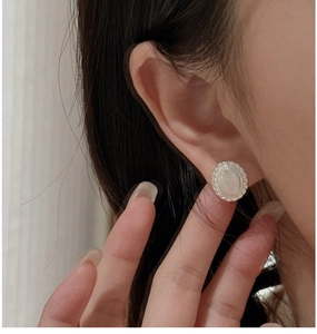 Macro shot of silver round stud earrings featuring rope-style edges and white inlay