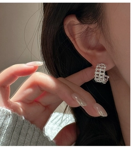 Close-up of S925 sterling silver woven C-shape earrings on model's ear with retro texture