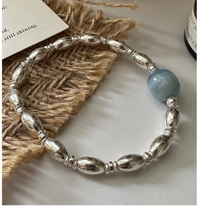 Detail of silver beaded bracelet featuring a large light blue natural gemstone bead